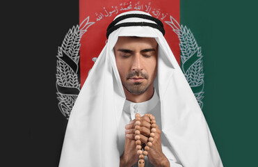Praying Muslim man with tasbih against flag of Afghanistan