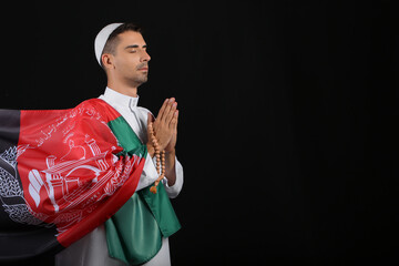 Praying Muslim man with flag of Afghanistan on dark background