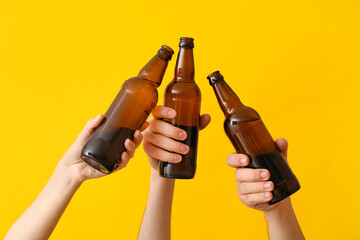 Hands with bottles of beer on color background