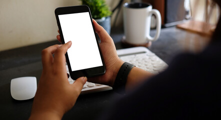 Young woman sitting at her workplace and using smart phone.