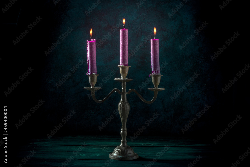 Wall mural Burning candles in a vintage candle holder on a dark background