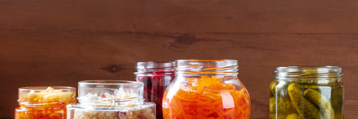 Fermented, probiotic foods panorama. Canned vegetables. Pickled carrot, gherkins and other organic preserves in glass jars. Healthy vegan cooking background with copy space