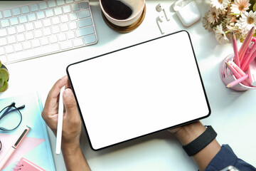 Overhead view creative man holding stylus pen and working with digital tablet on white table.