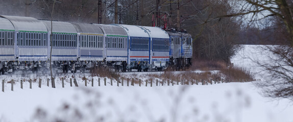 EXPRESS TRAIN - Passenger train goes along  trail against background of winter fields 