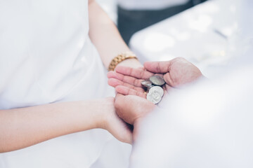 Groom palms holding the Unity Coins known as Las Arras or Arrhae over the bride's palms during the...