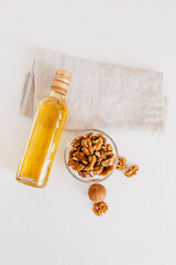 Walnut or olive oil in glass of bottle, whole big peeled walnut kernel with thin shell on white background. healthy food for brain. Fresh walnuts background nut concept
