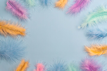 Fototapeta na wymiar Frame boarder made of feathers on blue background. Backdrop for designers