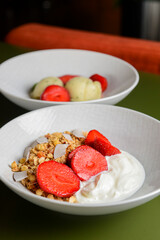 Bowl of hot oatmeal with fresh strawberries cut. Perfect as a healthy breakfast. Served with sour cream in a white bowl.
