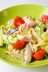 A plate of penne pasta with creamy sauce and a sprinkling of cheese with sliced cherry tomatoes