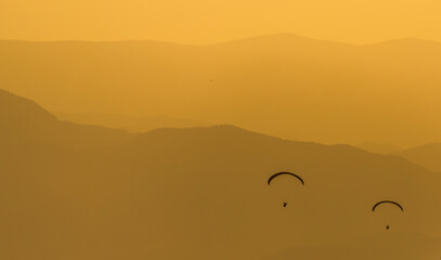 Fototapeta na wymiar sunset in the mountains with paraglider