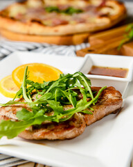 Gourmet grilled steak flavoured served with fresh green arugula, orange slices and tomato sauce.