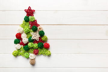 Fototapeta na wymiar Christmas tree made from colored handmade ball decoration on colored background, view from above. New Year minimal concept with copy space