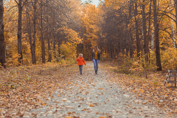 Mother and son walking in the fall park and enjoying the beautiful autumn nature. Season, single parent and children concept.