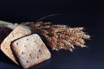 Fresh loaves of bread with wheat and gluten on a black table. Bakery and grocery concept. Fresh,...