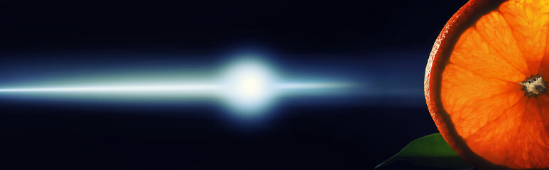 Composition with orange and grapefruit slices on a black background. A slice of orange with back light on a black background with water drops. Juicy orange on a table.