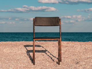 Black beach chair on empty sand beach with blue sea water background. Minimalism style autumn...