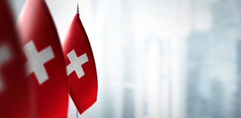Small flags of Switzerland on a blurry background of the city
