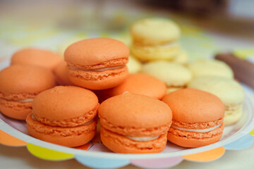 Close-up of a plate of orange and yellow french macarons