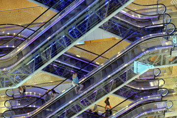 Glass escalator with people in a shopping center.