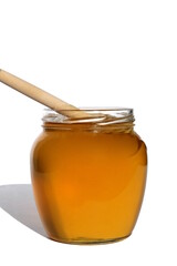 Glass jar with delicious fresh honey. There is a wooden ladle nearby. White isolated background.