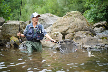 young woman fly fishing in a mountain river
