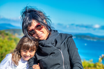 Happy woman with her daugher relaxing among foliage landscape in autumn season.