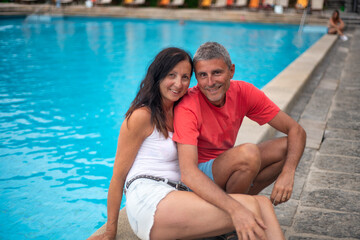 Fototapeta na wymiar Beautiful couple of people in the fifties relaxing at pool side.