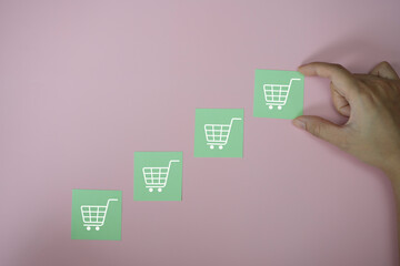 Closeup hands holding icon paper cut  with icon shopping cart symbol, sale volume increase make...