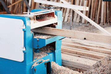 A wood plate passing through the thickness planer machine in a carpentry workshop. - obrazy, fototapety, plakaty