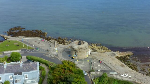 Martello Tower, Seapoint, Monkstown, Dublin, Ireland, September 2021. Drone gradually orbits the tower while descending revealing the bathing area and daytime swimmers.