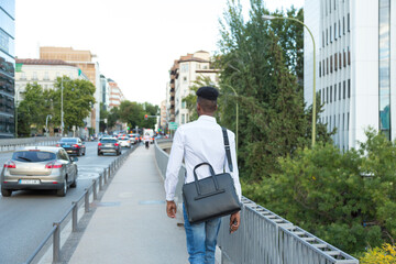 young african american businessman in white shirt and briefcase walking down the street