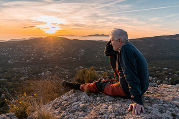 Senior man with head in hand sitting at cliff during hiking