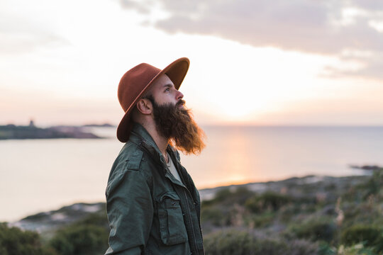 Man with long beard wearing hat during sunset