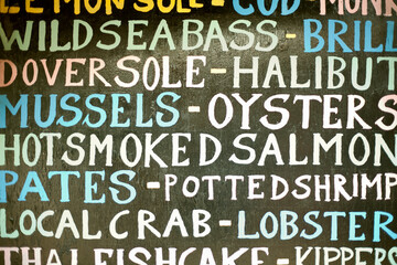 Hand painted sign listing seafood items
