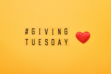 Giving Tuesday text message. Global day of charitable giving after Black Friday shopping day. Red heart on yellow background