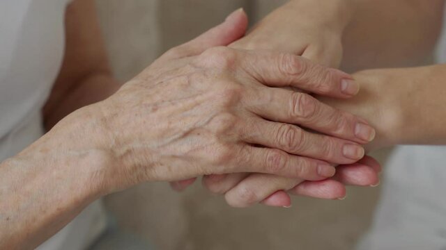 An elderly mother calms her daughter, strokes her, holds her hand in close-up.