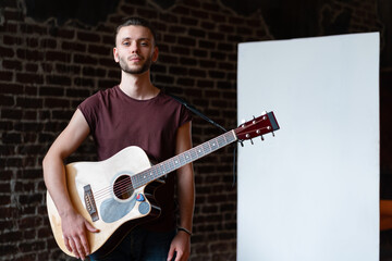 Man with acoustic guitar standing near whiteboard Music school concept