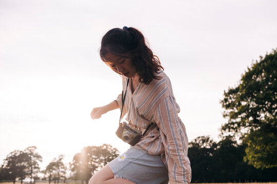 Young woman with camera standing at park
