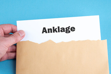 Eine Hand nimmt eine Anklage aus einem Briefumschlag