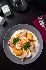 Colorful yellow hard boiled free range eggs in a creamy and mustard sauce served garnished with fresh herbs top view, flat lay
