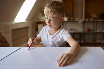 Little boy drawing at table, kid in art workshop