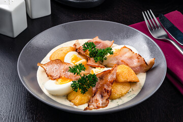 Colorful yellow hard boiled free range eggs in a creamy and mustard sauce served garnished with fresh herbs