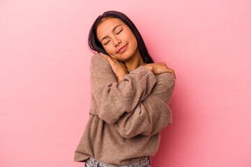 Young latin woman isolated on pink background  hugs, smiling carefree and happy.