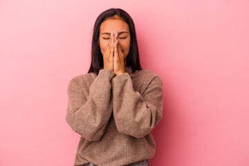 Young latin woman isolated on pink background  holding hands in pray near mouth, feels confident.