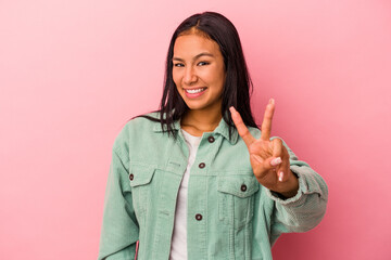 Young latin woman isolated on pink background  showing victory sign and smiling broadly.