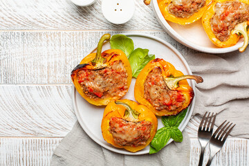 Bell peppers stufed with beef meat, rice, tomatoes and cheese, top view. On white wooden table.