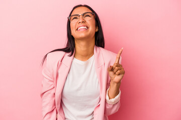 Young latin woman isolated on pink background  indicates with both fore fingers up showing a blank space.
