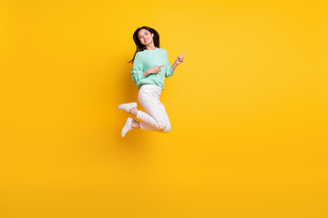 Fototapeta na wymiar Full body photo of positive happy woman point finger empty space jump up isolated on yellow color background