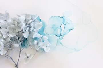 Creative image of pastel blue Hydrangea flowers on artistic ink background. Top view with copy space