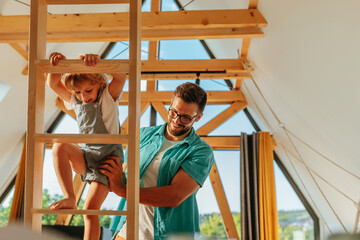 Girl climbing ladder with the help of her father
